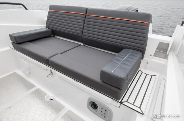 Sleek grey boat seating with orange accents, featuring a cushioned backrest and side armrest, beside a minimalist side table.